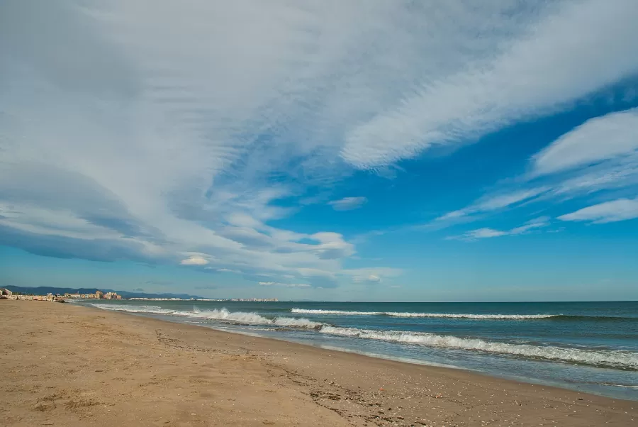 Sandy beach and waves on the Valencia seafront under a blue sky